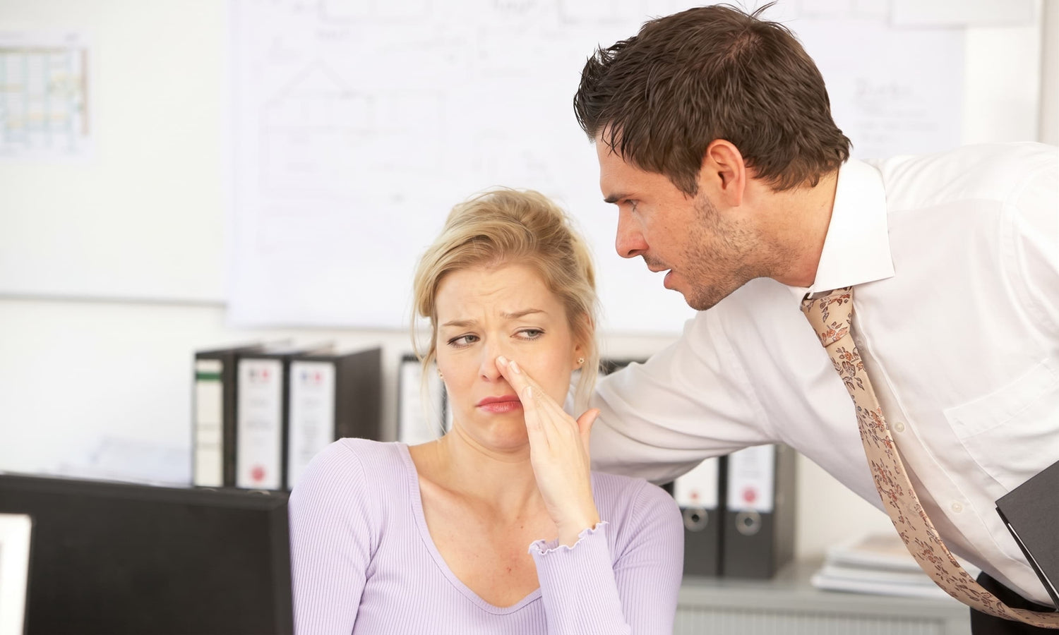 Man and woman in an office setting with a serious conversation.
